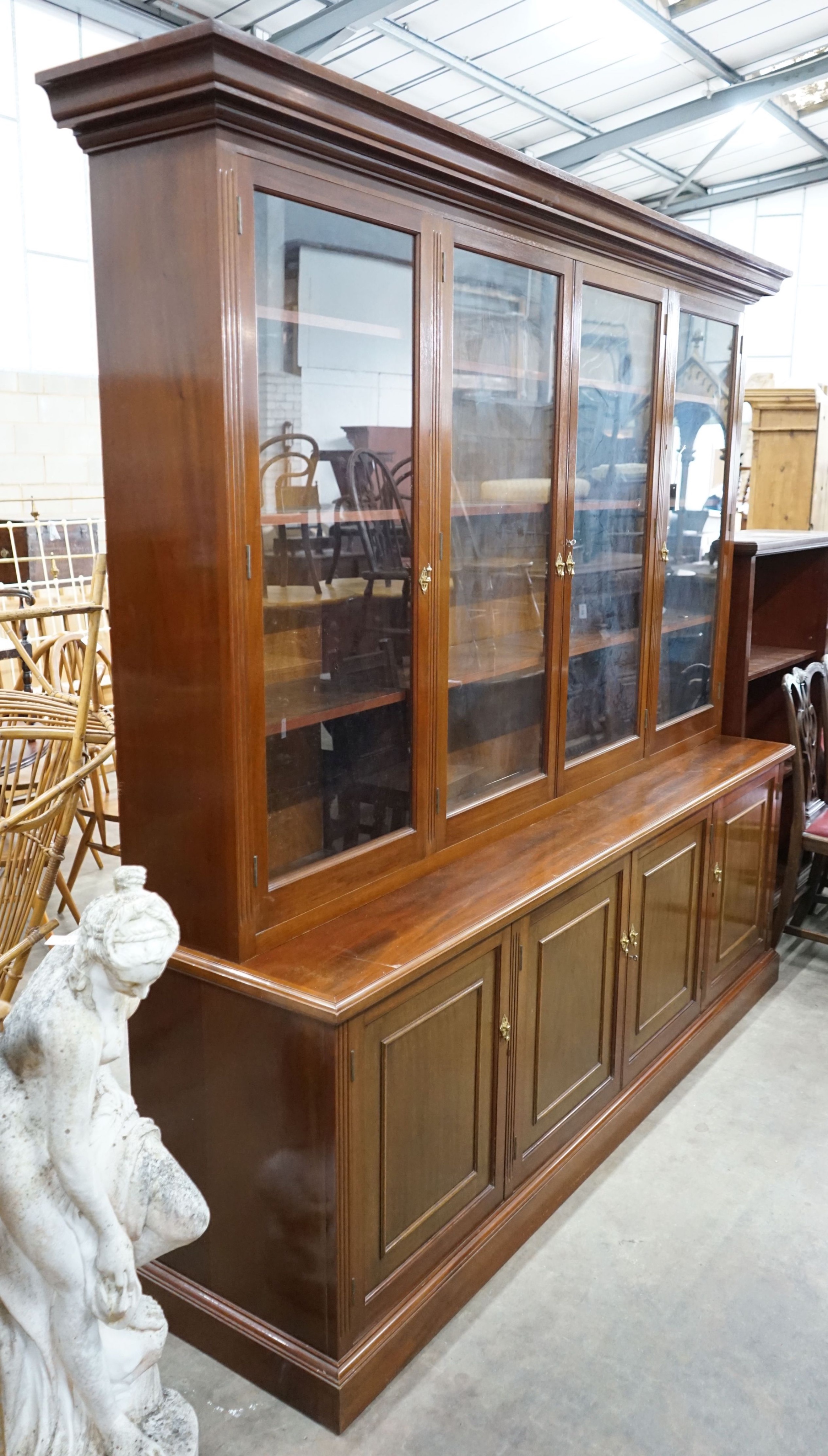 A Victorian style four section mahogany library bookcase, the upper section fitted clear glazed doors above further panelled doors on plinth base, length 216cm, depth 51cm, height 215cm